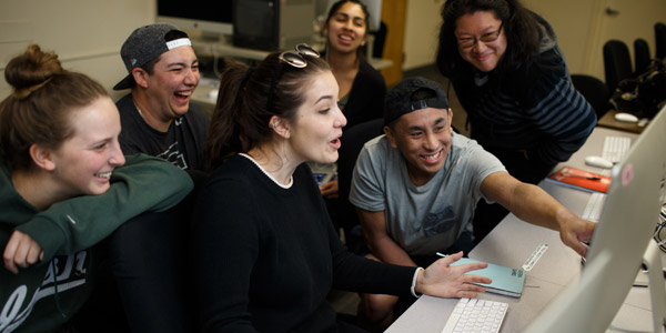 Group of students laughing as one points to the image on the computer